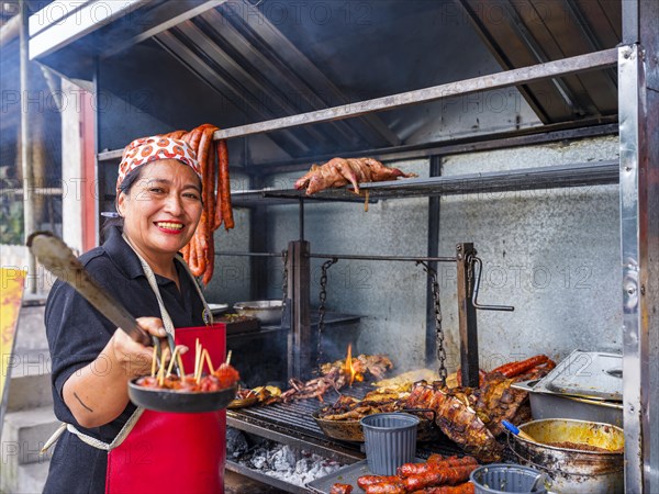 Woman at a street barbecue with lots of meat and sausage