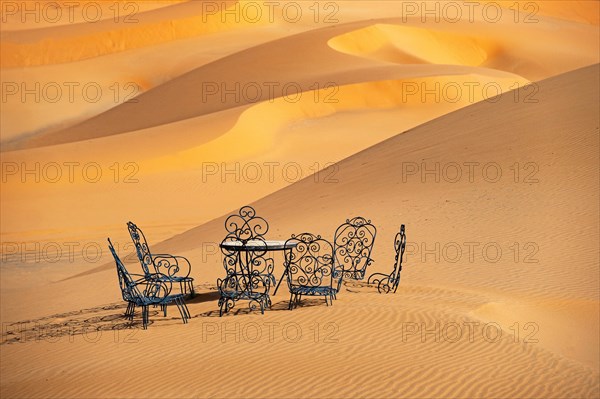 Cast iron garden table and lawn chairs in sand dunes of Erg Chebbi in the Sahara Desert near Merzouga