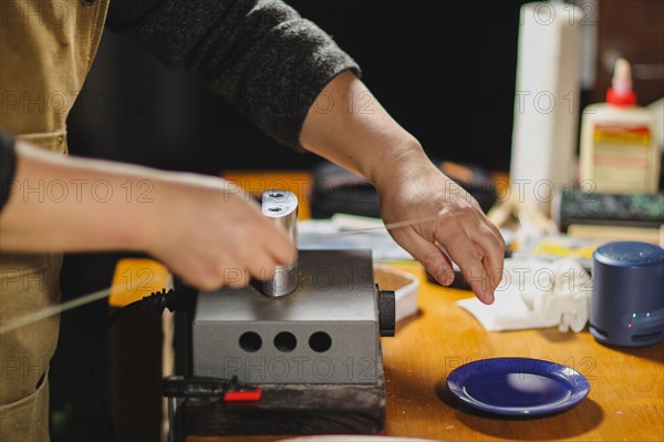 Unrecognizable luthier lute maker artisan both hands performing bend controller purfling strips process in iron tool for a new raw back and front plates of classic handmade violin in his workshop in Cremona