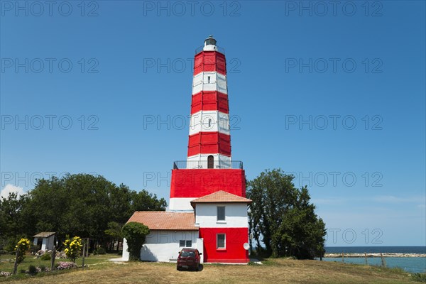 Red and white striped lighthouse on a sunny day with a clear blue sky and calm sea