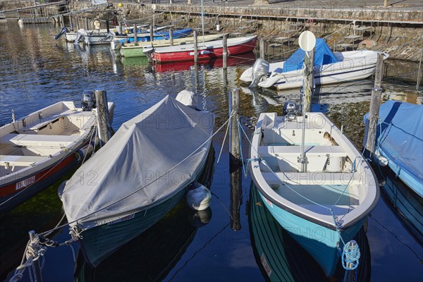 Motorboats moored in the harbour of Ascona and partially protected by a tarpaulin