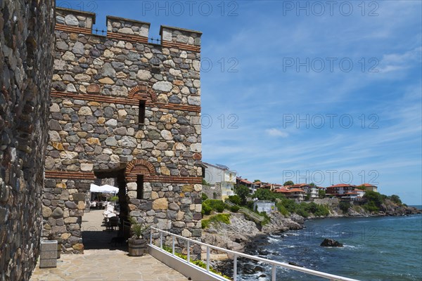 Ancient stone tower on a rocky coast with clear blue sky and calm sea