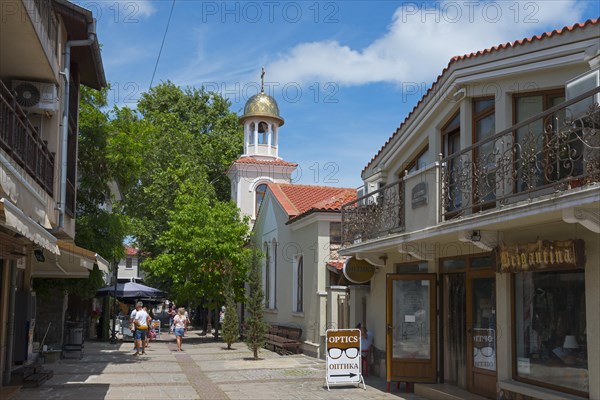 Pedestrian zone with people strolling between shops and a church