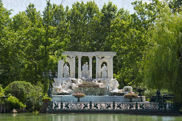 A magnificent fountain with statues and columns surrounded by green vegetation under a clear sky