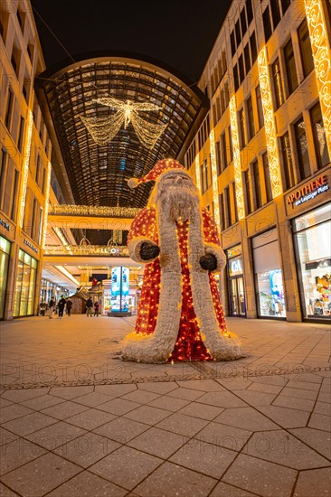 Pedestrian zone at night with a large illuminated Father Christmas and decorated shops