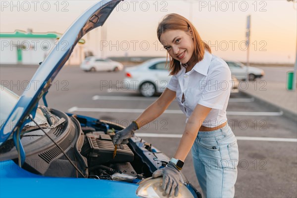 Young beautiful hot girl driver checks oil level