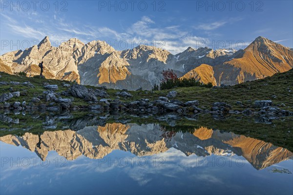 Hiker reflected in mountain lake in front of mountains, evening light, Guggersee, Allgaeu Alps, Allgaeu, Germany, Europe