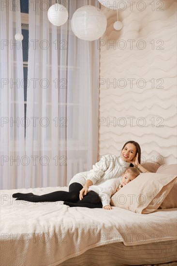 Happy young mother and daughter lying on the bed together