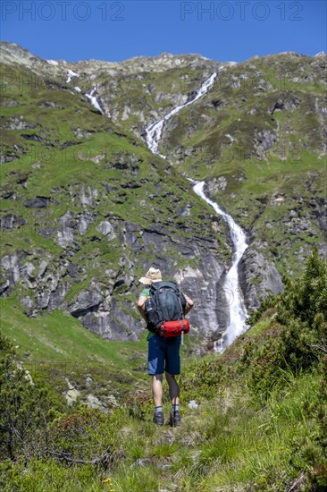 Mountaineer in front of a waterfall, Berliner Hoehenweg, Zillertal Alps, Tyrol, Austria, Europe