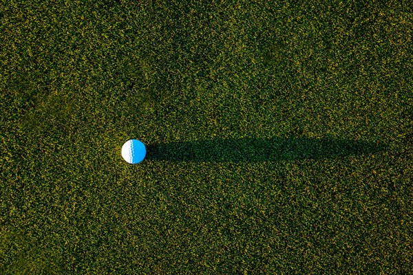 Golf Ball on the Grass with Shadow on Putting Green on Golf Course in Sunset in Switzerland
