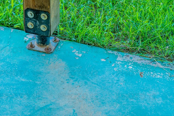 Square wooden support column attached to concrete base using metal anchor plate