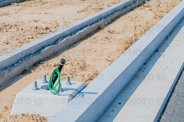 Electrical wiring protruding from newly installed lamppost base next to curb at construction site