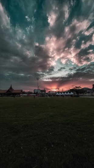 A vibrant sunset over an open field with a dramatic cloud formation. Kampot, Cambodia, Asia