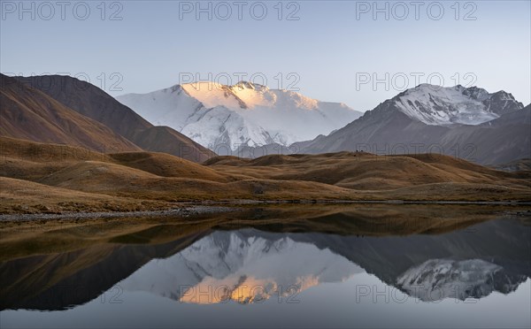 Mountain landscape at sunset, mountains reflected in a small mountain lake, Pik Lenin, Trans Alay Mountains, Pamir Mountains, Osh Province, Kyrgyzstan, Asia