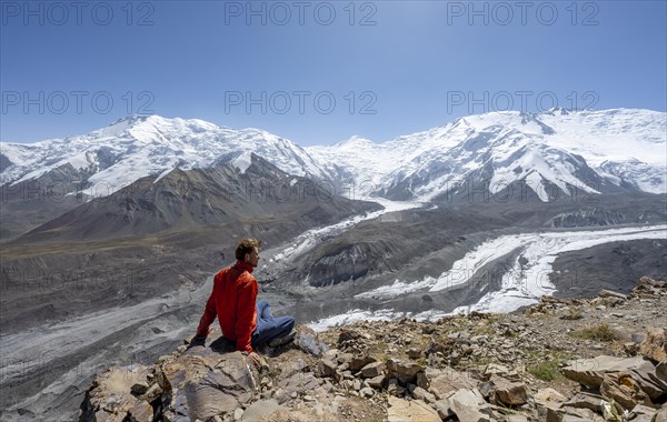 Mountaineer at Traveller's Pass with view of impressive mountain landscape, high mountain landscape with glacier moraines and glacier tongues, glaciated and snow-covered mountain peaks, Lenin Peak and Peak of the XIX Party Congress of the CPSU, Trans Alay Mountains, Pamir Mountains, Osh Province, Kyrgyzstan, Asia