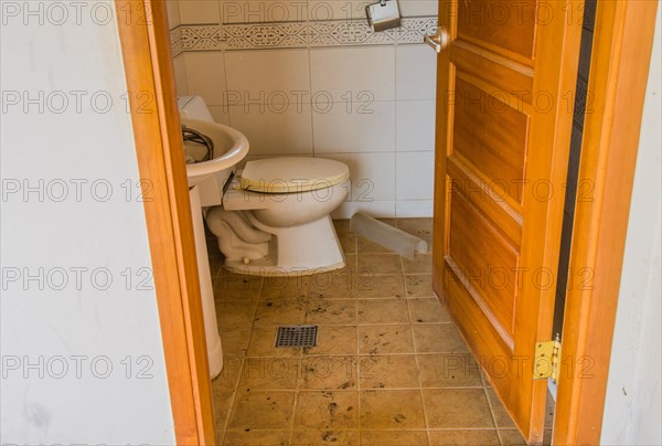 Grungy half-bath with sink full of debris and dirty commode in abandoned house