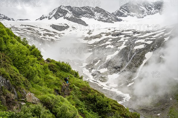 Mountaineers on a hiking trail, in the background glaciated peak Dosso Largo and glacier Schlegeiskees, cloudy atmospheric mountain landscape, ascent to Furtschaglhaus, Berliner Hoehenweg, Zillertal, Tyrol, Austria, Europe