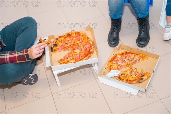 Top view of unrecognizable three people eating delivery pizzas while moving