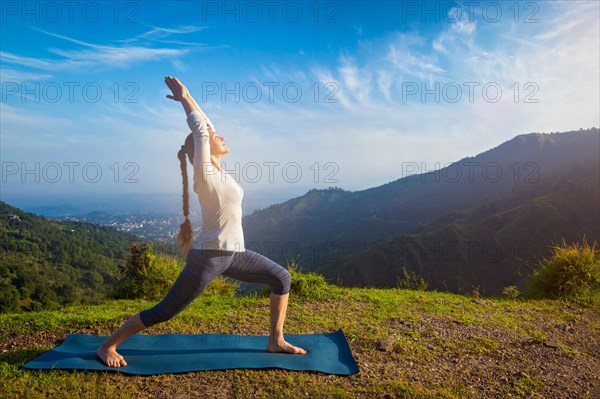 Yoga outdoors, woman doing yoga asana Virabhadrasana 1, Warrior pose posture outdoors in Himalayas mountains in the morning