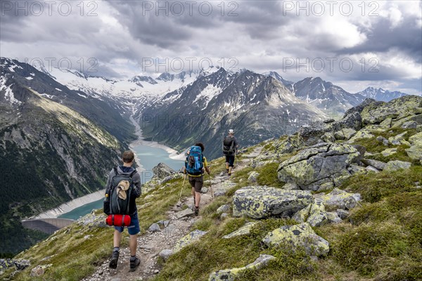 Mountaineer on hiking trail, view of Schlegeisspeicher, glaciated rocky mountain peaks Hoher Weisszint and Hochfeiler with glacier Schlegeiskees, Berliner Hoehenweg, Zillertal Alps, Tyrol, Austria, Europe