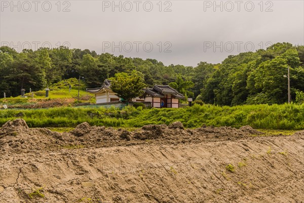 Daejeon, South Korea, May 22, 2018: Korean building with perimeter wall and ceramic tile roof in front of small family grave site in rural South Korea, Asia