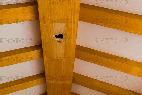 Large hole in center beam of living room ceiling in abandoned house