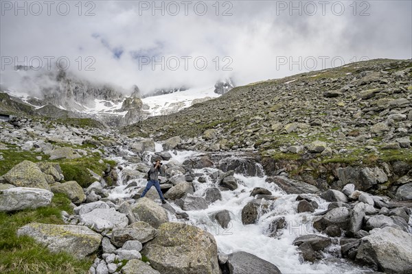 Mountaineers photographed, at a mountain stream, Furtschaglbach, behind rocky mountains with glacier Furtschaglkees, Furtschaglhaus, Berliner Hoehenweg, Zillertal, Tyrol, Austria, Europe