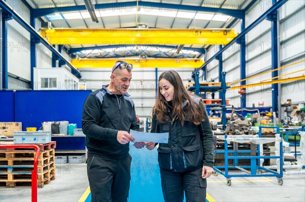 Engineers talking and looking at a paper while working in a cnc logistics factory