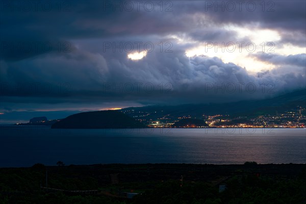 Night view of an illuminated coastal town of Horta under dramatic clouds, Horta, Faial, Azores, Portugal, Europe