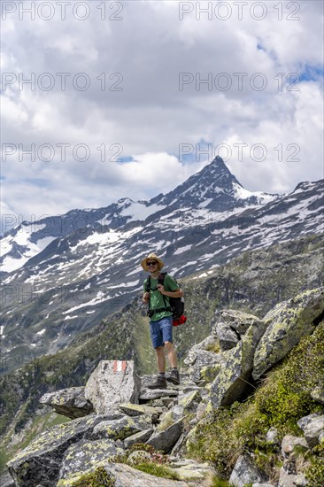 Mountaineer on rocky hiking trail, Berliner Hoehenweg, mountain panorama with summit Schrammacher, Zillertal Alps, Tyrol, Austria, Europe