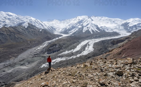 Mountaineer at Traveller's Pass with view of impressive mountain landscape, high mountain landscape with glacier moraines and glacier tongues, glaciated and snow-covered mountain peaks, Lenin Peak and Peak of the XIX Party Congress of the CPSU, Trans Alay Mountains, Pamir Mountains, Osh Province, Kyrgyzstan, Asia