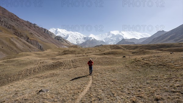 Mountaineers in the Achik Tash valley, in the background glaciated and snow-covered mountain peak Lenin Peak and Peak of the XIX Party Congress of the CPSU, Trans Alay Mountains, Pamir Mountains, Osh Province, Kyrgyzstan, Asia