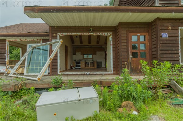 Daejeon, South Korea, June 29, 2018: Old refrigerator laying in front of abandoned two story house, Asia