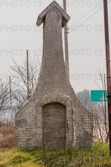 Small wire-frame and stucco building resembling a church in grassy area next to highway