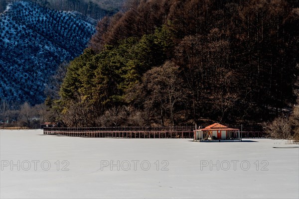 Winter landscape of fishing hut floating on frozen snow covered lake