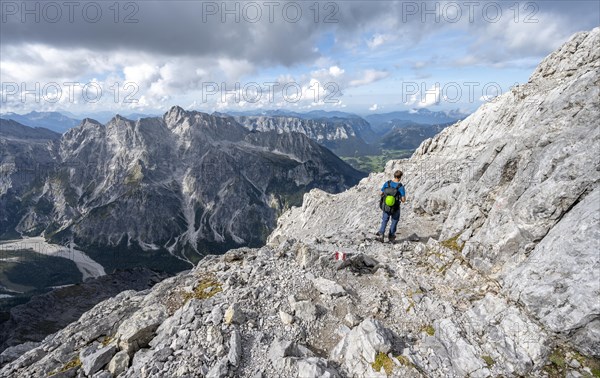 Mountaineer on a narrow rocky ridge, Watzmann crossing to the Watzmann Mittelspitze, view of mountain panorama with Hochkalter massif, Berchtesgaden National Park, Berchtesgaden Alps, Bavaria, Germany, Europe