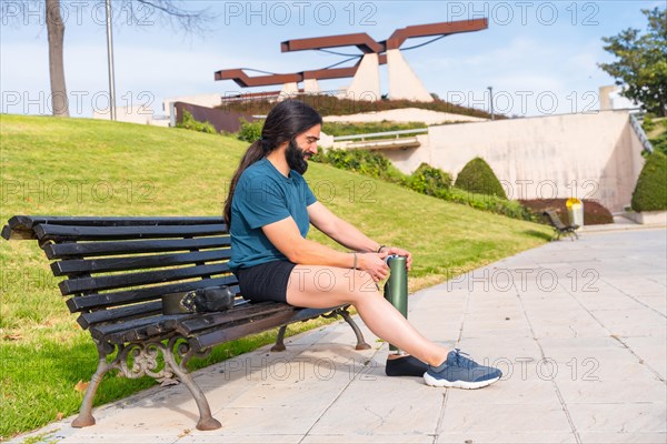 Active man adjusting his prosthetic leg before running outdoor in the park