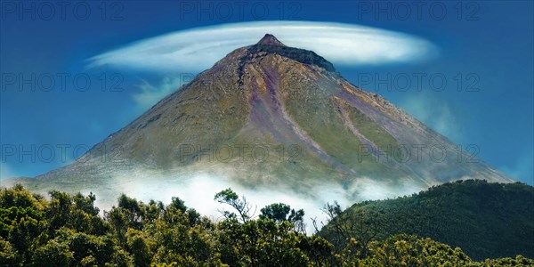 Pico volcano with a lenticularis cloud in the blue sky, surrounded by vegetation, Gruta das Torres, Pico Island, Azores, Portugal, Europe