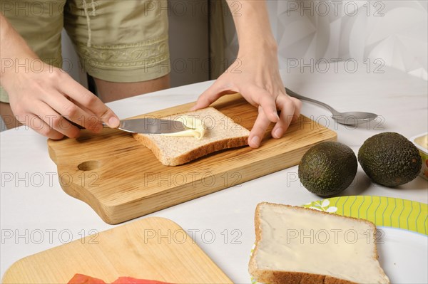 Hands of woman spreading soft cheese on toast