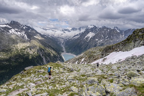 Two mountaineers on hiking trail, view of Schlegeisspeicher, glaciated rocky mountain peaks Hoher Weisszint and Hochfeiler with glacier Schlegeiskees, Berliner Hoehenweg, Zillertal Alps, Tyrol, Austria, Europe