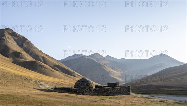 Historic caravanserai Tash Rabat from the 15th century, in the evening light with golden hills, Naryn region, Kyrgyzstan, Asia