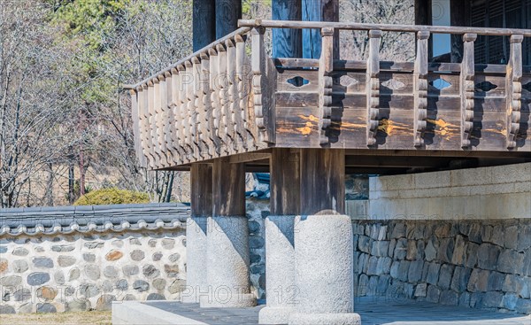 Wooden gazebo on concrete pillars surrounded by a stone wall in a local woodland park in South Korea
