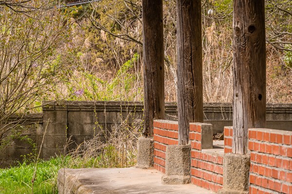 Inside view of old oriental style covered pavilion surrounded by a concrete wall in an overgrown woodland area in South Korea