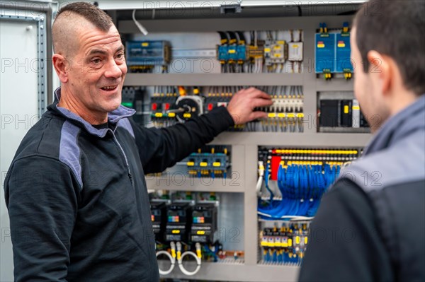 Two male workers of industrial technician installing and maintenance electrical mechanical systems in a factory