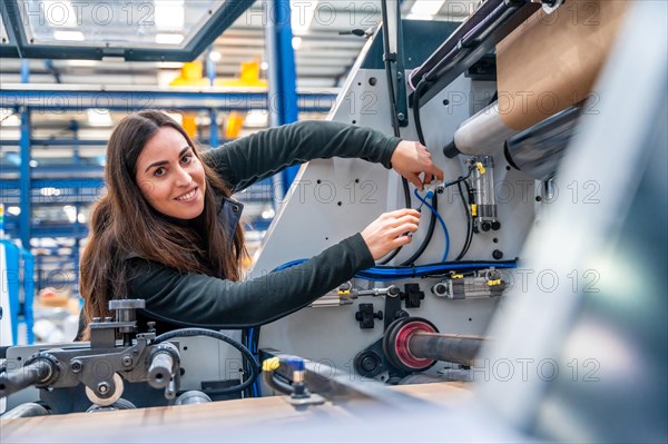 Smiling engineer looking at camera while repairing a cnc machine in a modern logistic factory