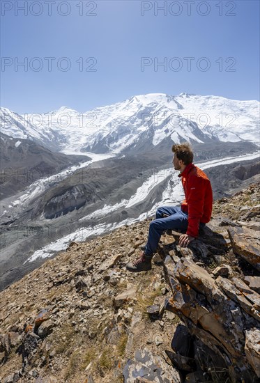 Mountaineer at Traveller's Pass with view of impressive mountain landscape, high mountain landscape with glacier moraines and glacier tongues, glaciated and snow-covered mountain peaks, Lenin Peak and Peak of the XIX Party Congress of the CPSU, Trans Alay Mountains, Pamir Mountains, Osh Province, Kyrgyzstan, Asia