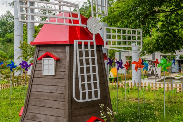 Miniature windmill in front of colorful pinwheels at roadside park