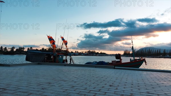 Sunset view over the river with silhouette of moored traditional khmer fishing boat in Kampot Cambodia