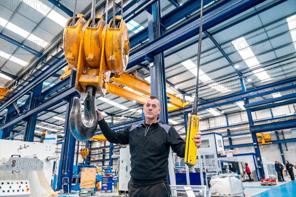 Worker on duty using an industrial crane in a logistics factory