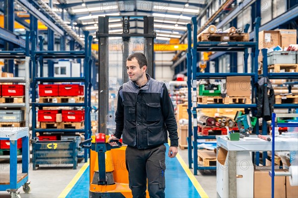 Manual worker carrying a handcart in a warehouse of a logistic center